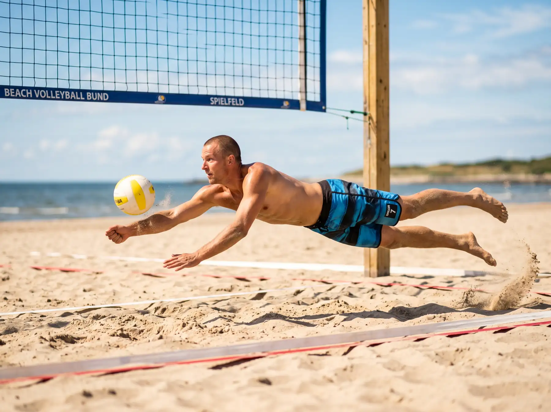 Beachvolleyball-Spieler bei einer Abwehraktion auf dem Sandfeld